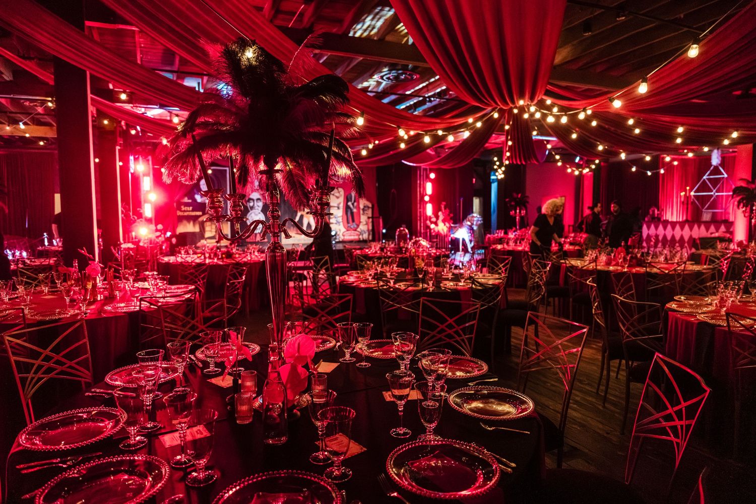 Panoramic view of a nightclub interior bathed in dramatic red lighting with tables and seating areas.