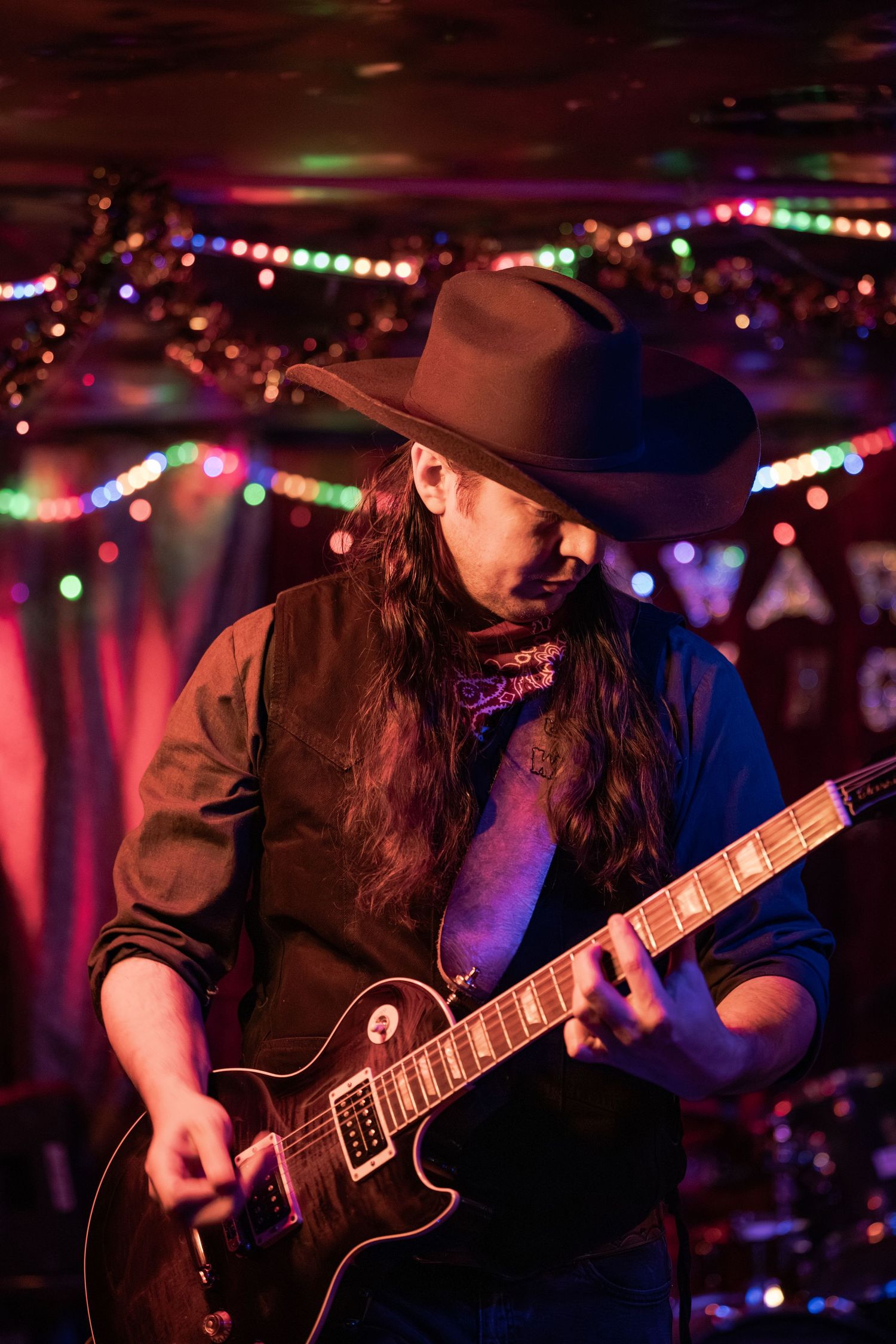 Guitar player performs on stage with colorful lights in the background creating an atmospheric concert ambiance.