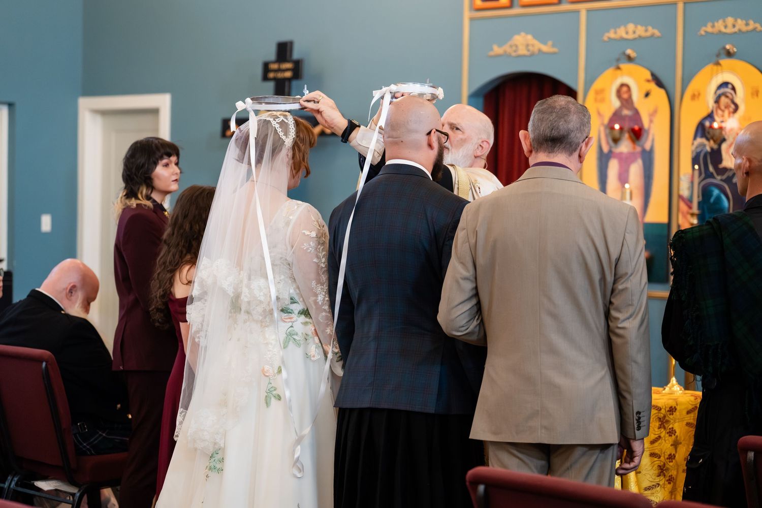 Wedding ceremony taking place in front of religious icons and artwork in a church setting.