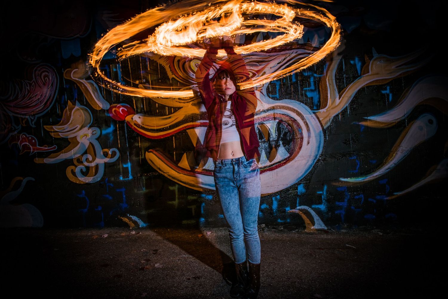 Person creates mesmerizing light trails with fire spinning performance art in dark urban setting at night.