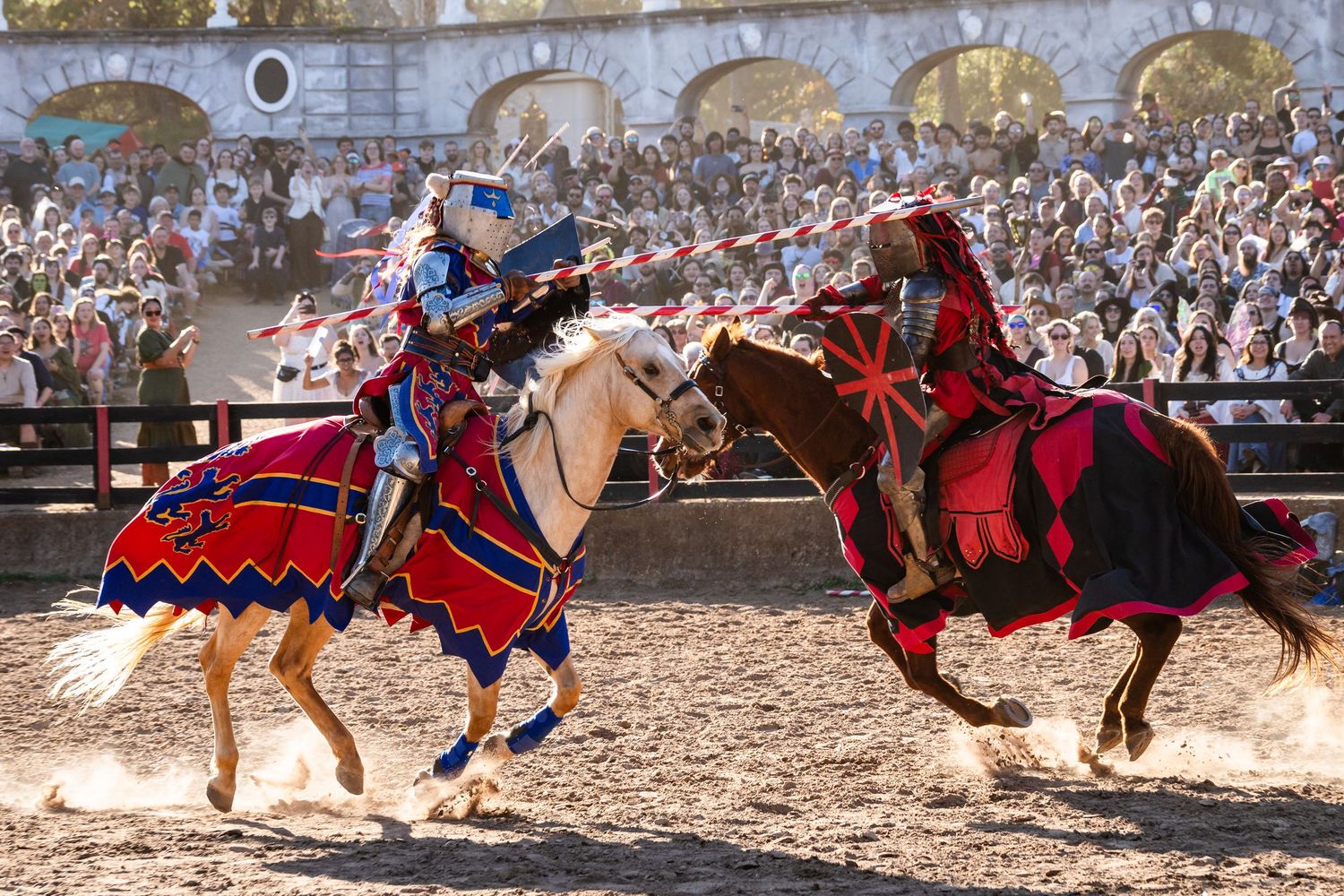 Medieval knights engage in a dramatic jousting tournament at a Renaissance festival with colorful banners and armor.