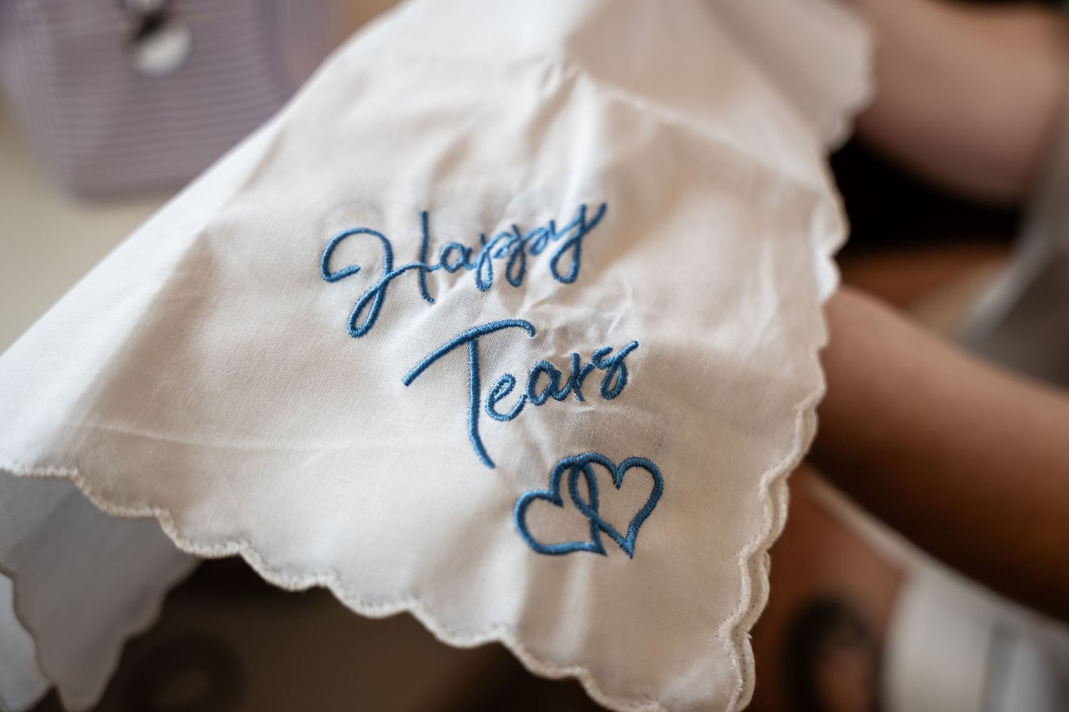 White embroidered handkerchief with blue cursive Happy Tears text and heart design, perfect wedding keepsake gift.