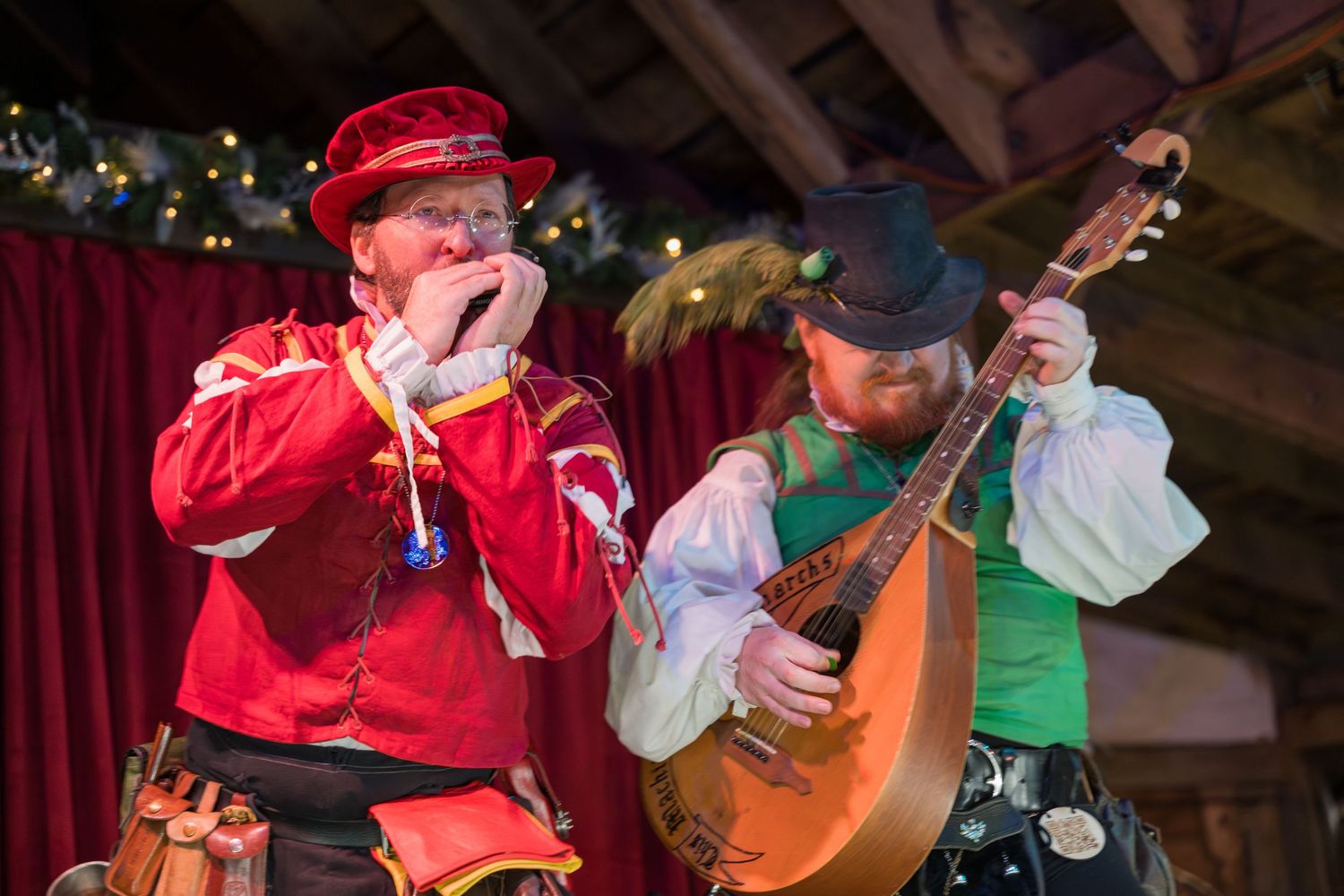 Musicians perform traditional folk music with string instruments and red attire at a rustic venue.