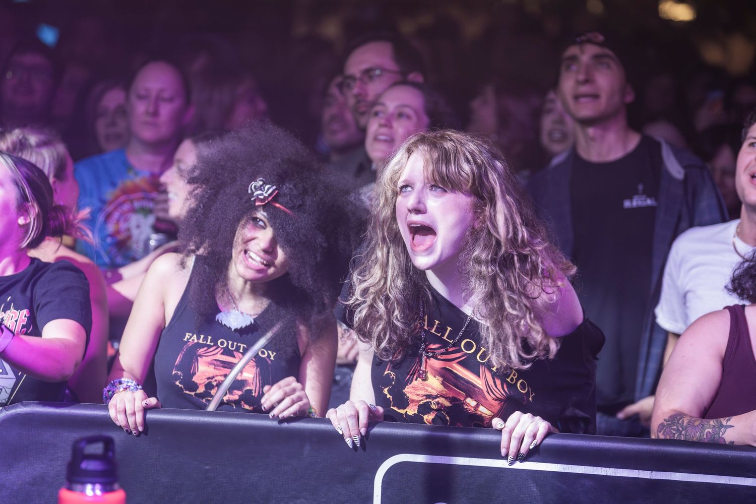 Concert crowd reacts emotionally during a performance with dramatic lighting and hands raised in the air.
