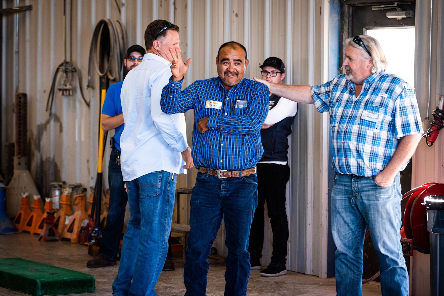People in blue work attire gather in a workshop or industrial space for a meeting or training session.