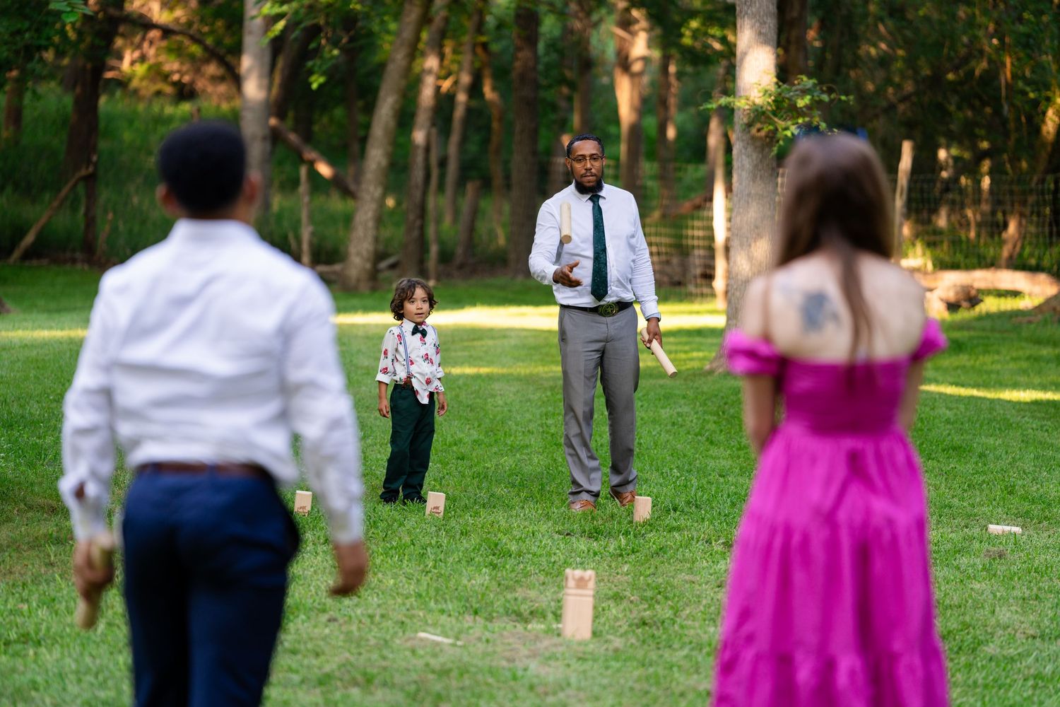 Adults and children playing a lawn game in a lush green park during a casual outdoor gathering.