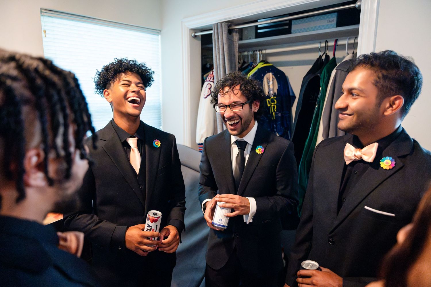 Groomsmen share a lighthearted moment while getting ready in formal attire before a wedding ceremony.