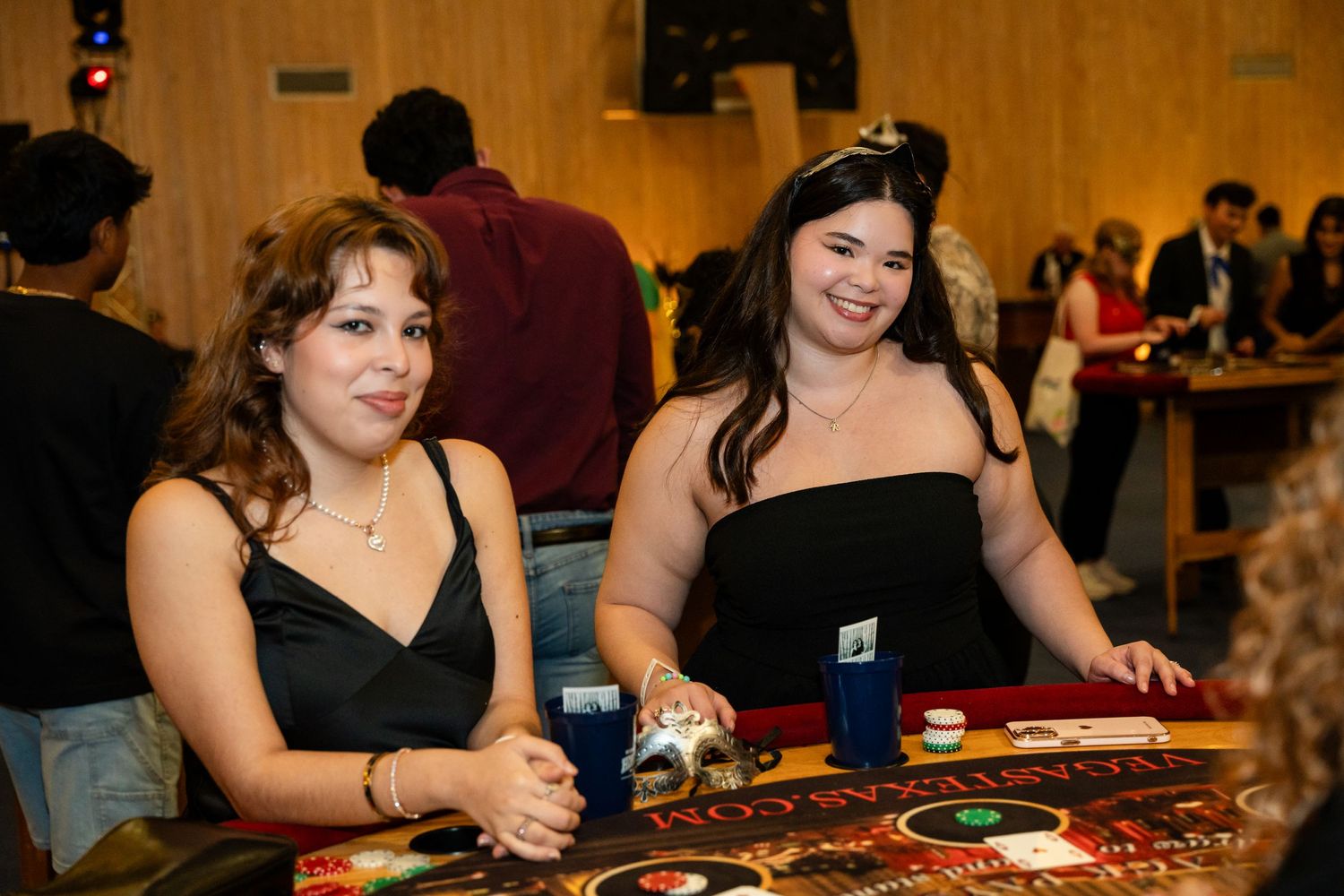 Two women in dark attire playing at a casino gaming table during an indoor event.