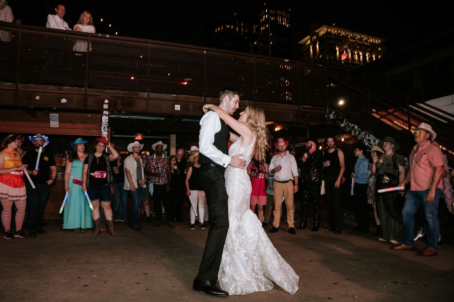 A couple shares their first dance at their wedding reception surrounded by guests.