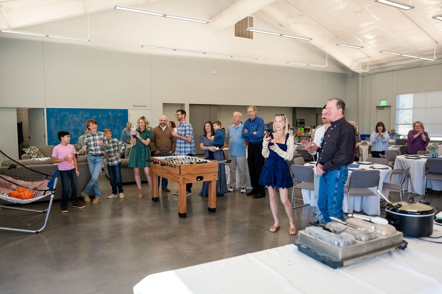 Group gathered around foosball table at casual indoor event.