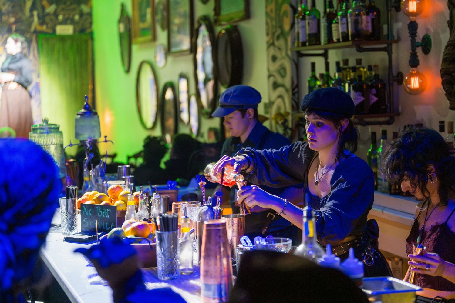 People seated at a dimly lit blue-tinted bar during an evening event.