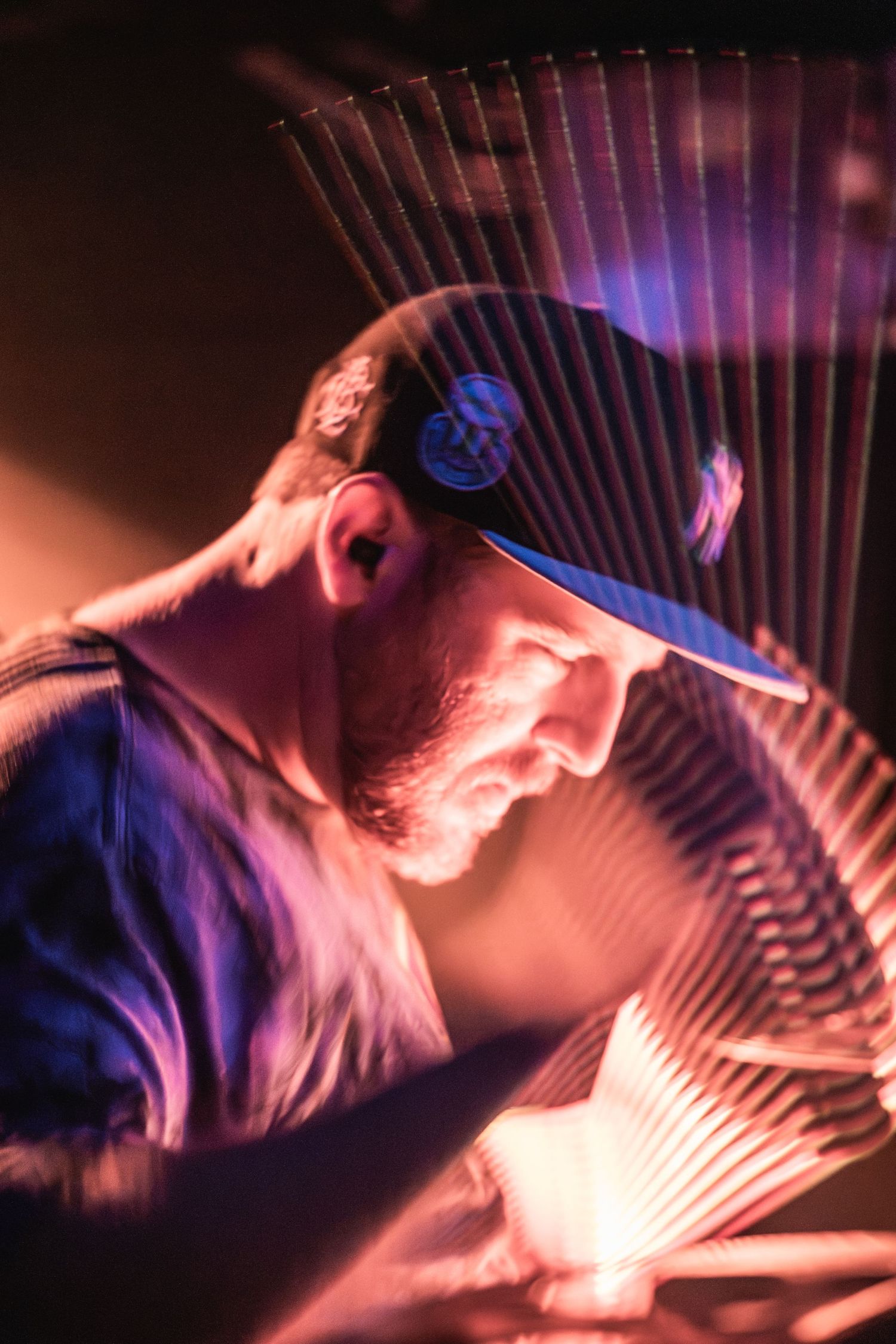 Artistic profile shot of performer with geometric light patterns and blue cap.