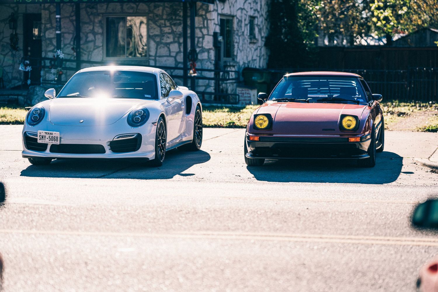 Modern Porsche 911 parked next to classic Mazda RX-7 showing automotive evolution.