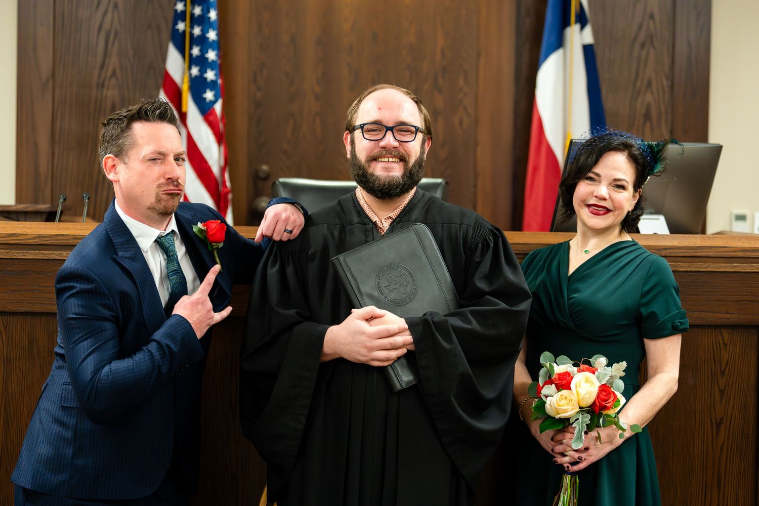 A cheerful courthouse wedding scene with three people posing playfully.