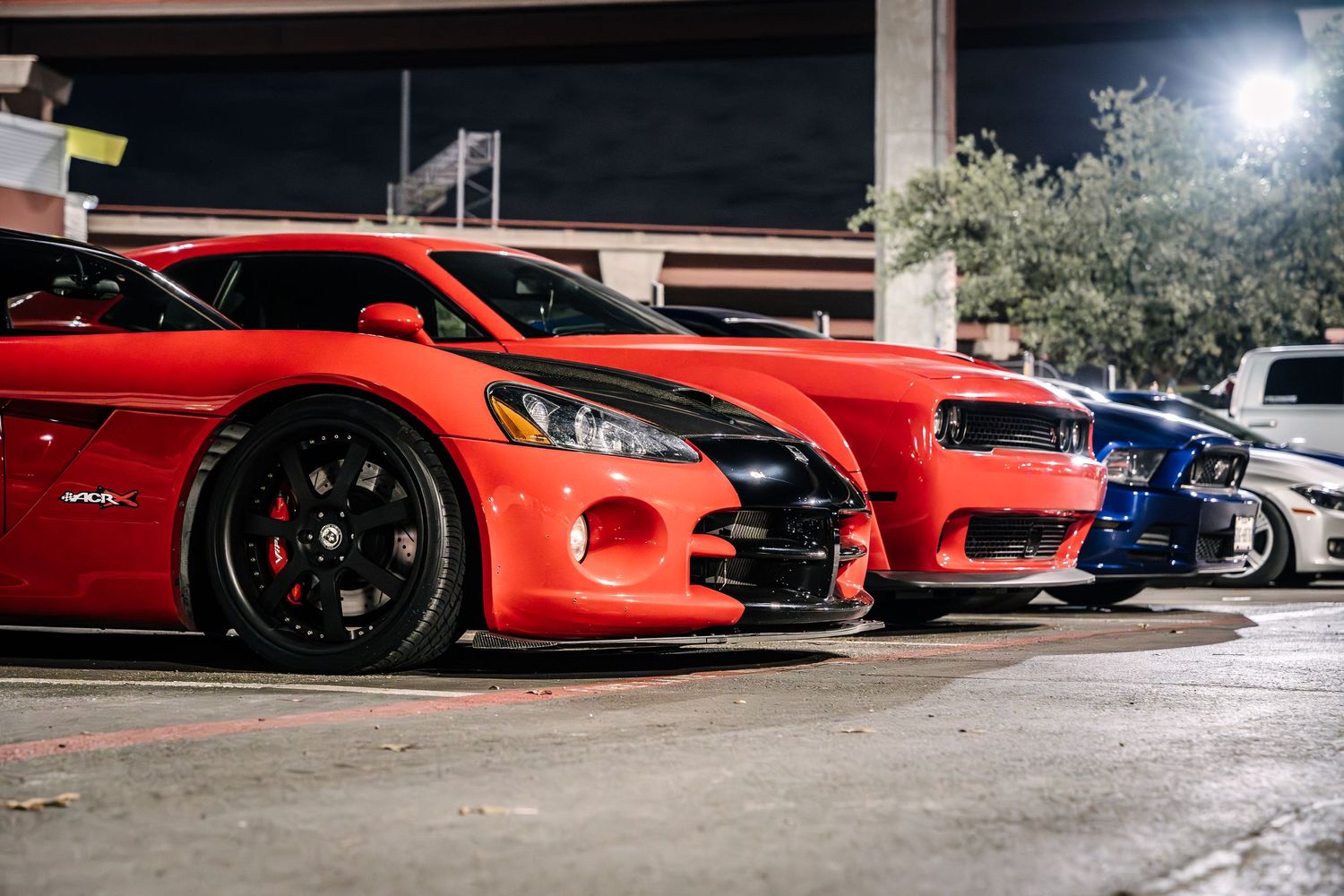 A row of colorful sports cars parked in a garage at night.