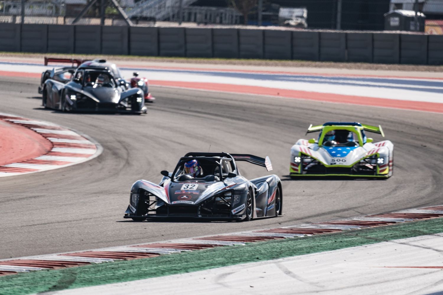 Two race cars compete closely through a corner on a professional racing circuit.
