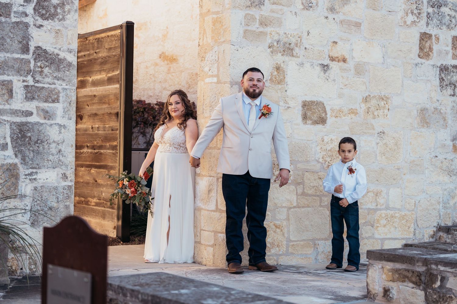 Wedding party standing in doorway of historic stone building.