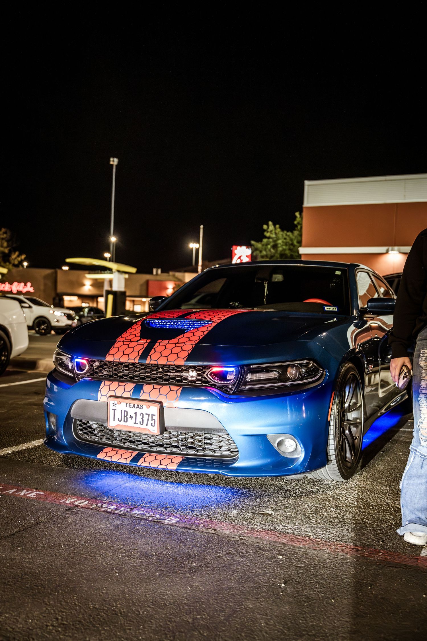 Modified blue Dodge Charger with LED underglow lights and racing stripes.