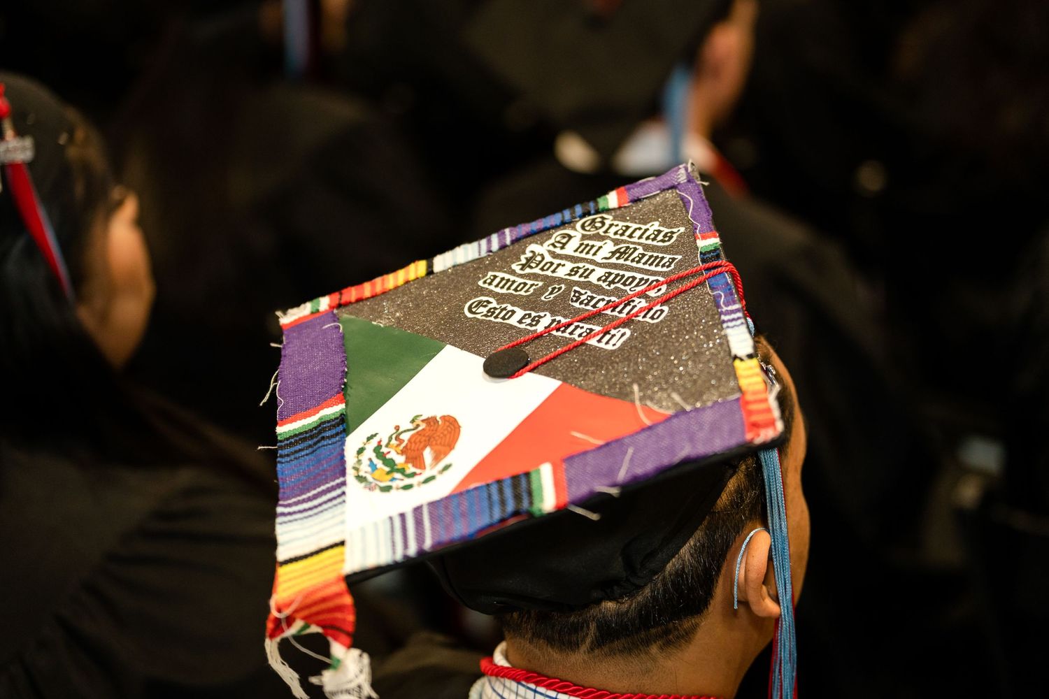 A decorated graduation cap featuring a Mexican flag design at a commencement ceremony.