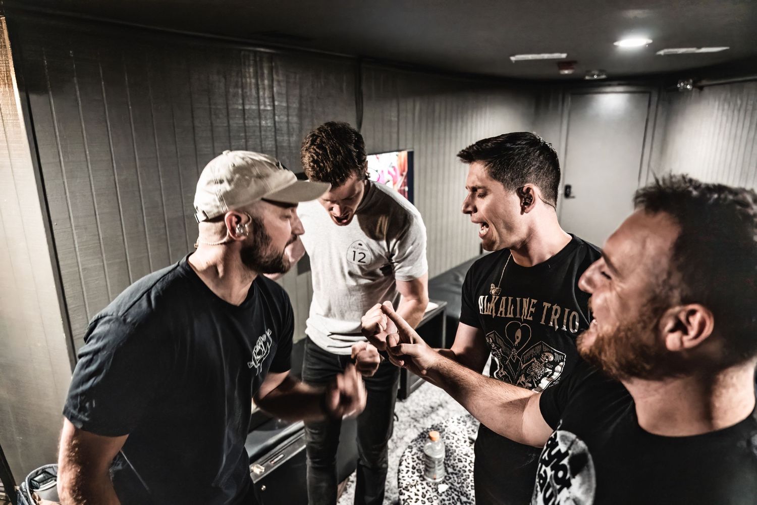 Band members share an intense moment backstage in dimly lit hallway during performance.