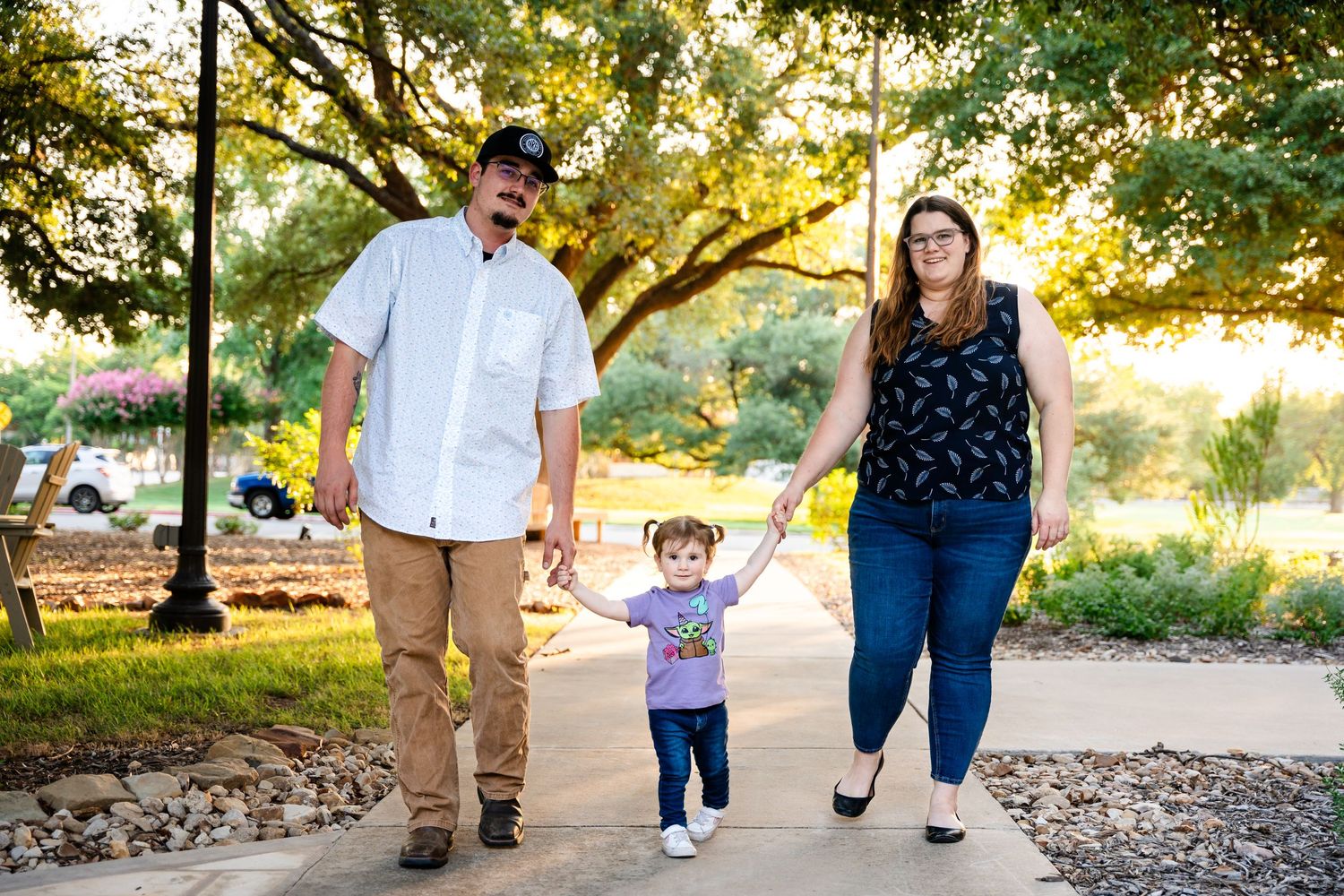 A family takes a sunset walk together on a tree-lined path.