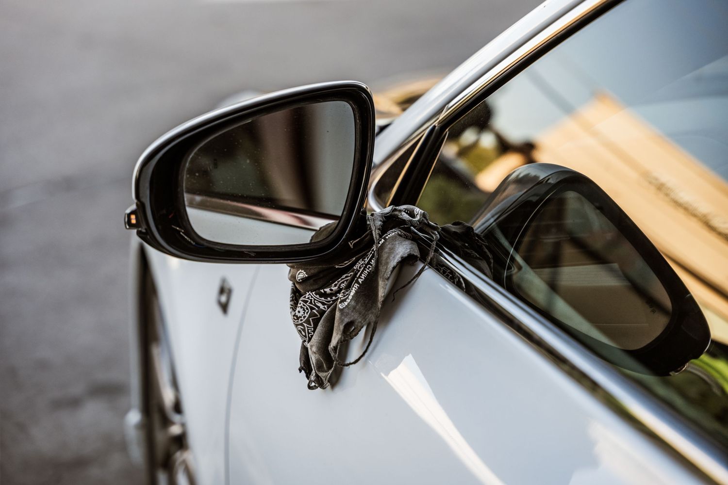 Detailed shot of a black side mirror on a white car with stylized design.