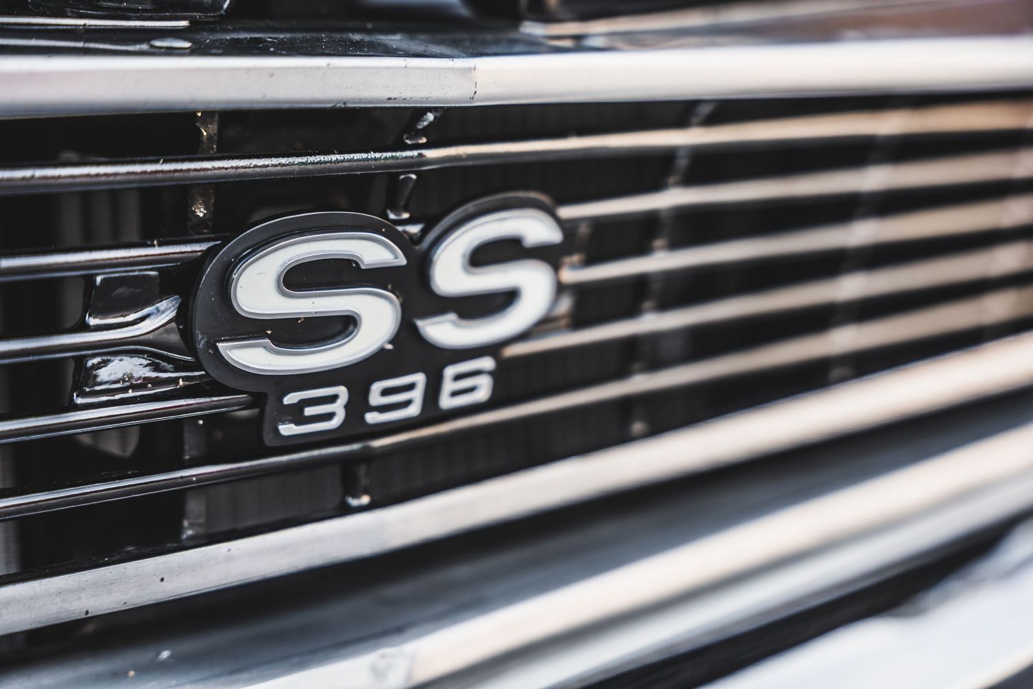 Chevrolet SS 396 chrome badge on black grille of classic muscle car.