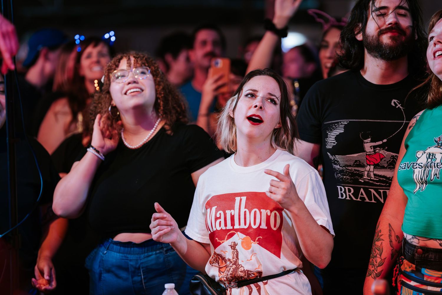 Enthusiastic concert crowd enjoying live music performance at indoor venue.