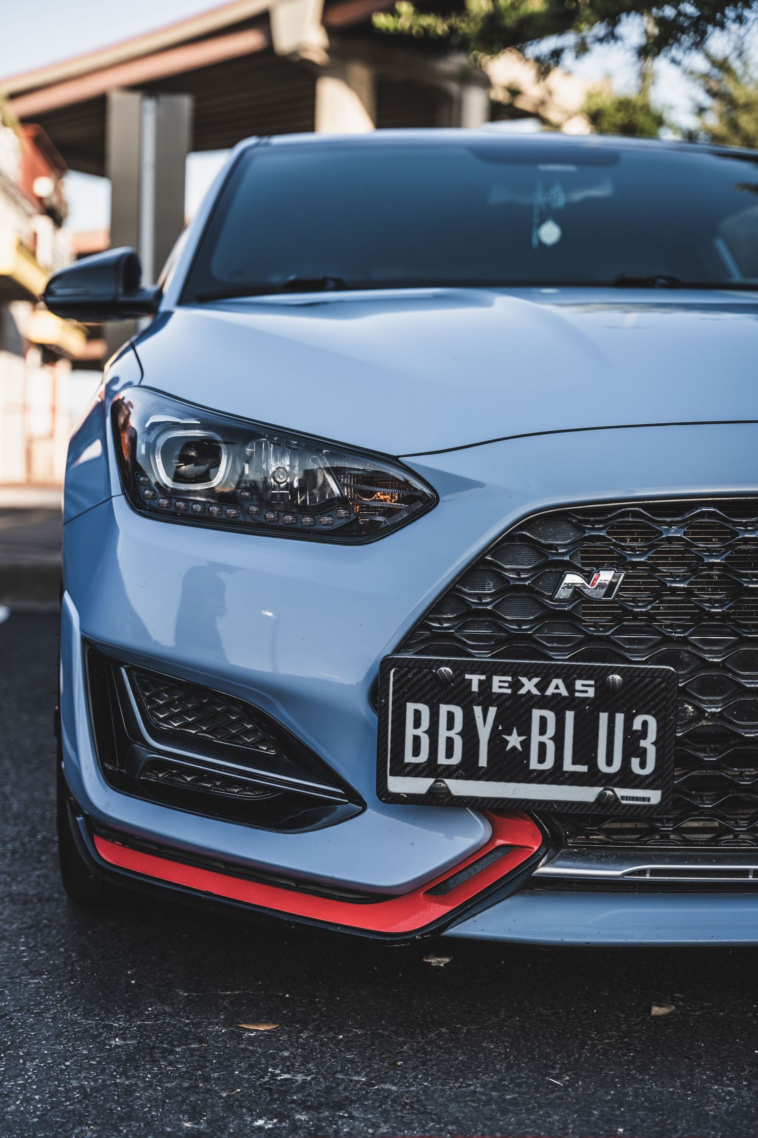 Close up of light blue Hyundai N model front end with Texas license plate and red accent trim.