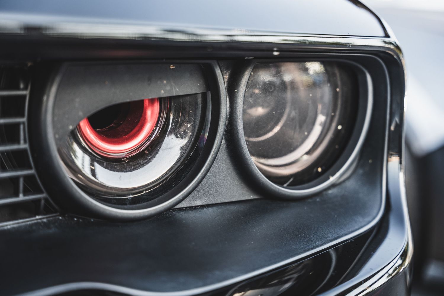 Close-up of aggressive red-ringed headlights on a modern sports car showing menacing front-end detail.
