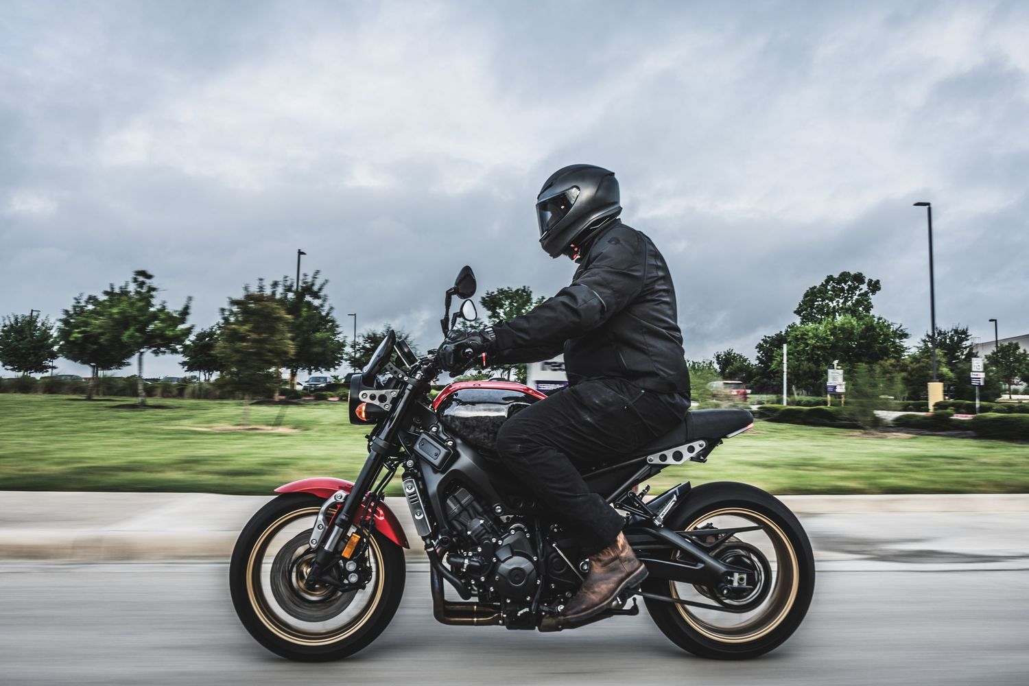 Motorcycle rider in black gear on a custom street bike during motion shot.
