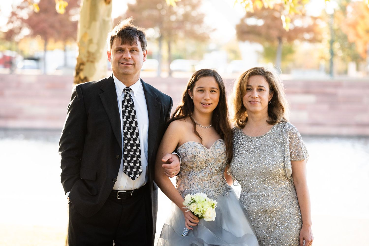 Family formal portrait outdoors wearing coordinated formal attire near water.