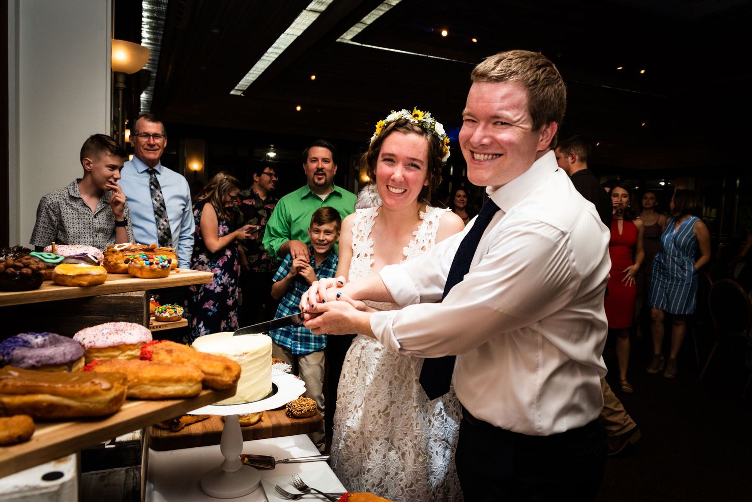 A couple cuts into their wedding desserts at a reception dessert table.
