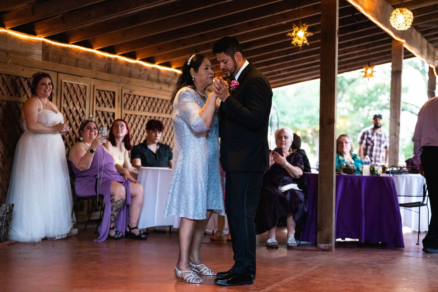 A couple dancing at an indoor reception venue with exposed wood beams and rustic decor.