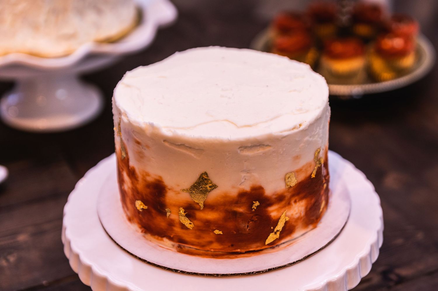 A modern wedding cake with white frosting and amber-colored design detail.