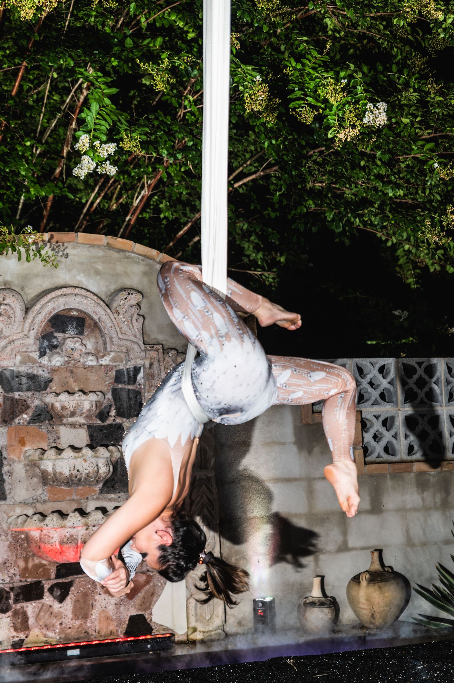 A dynamic aerial silk performance showcasing fluid movement against an ornate stone backdrop with ambient lighting.
