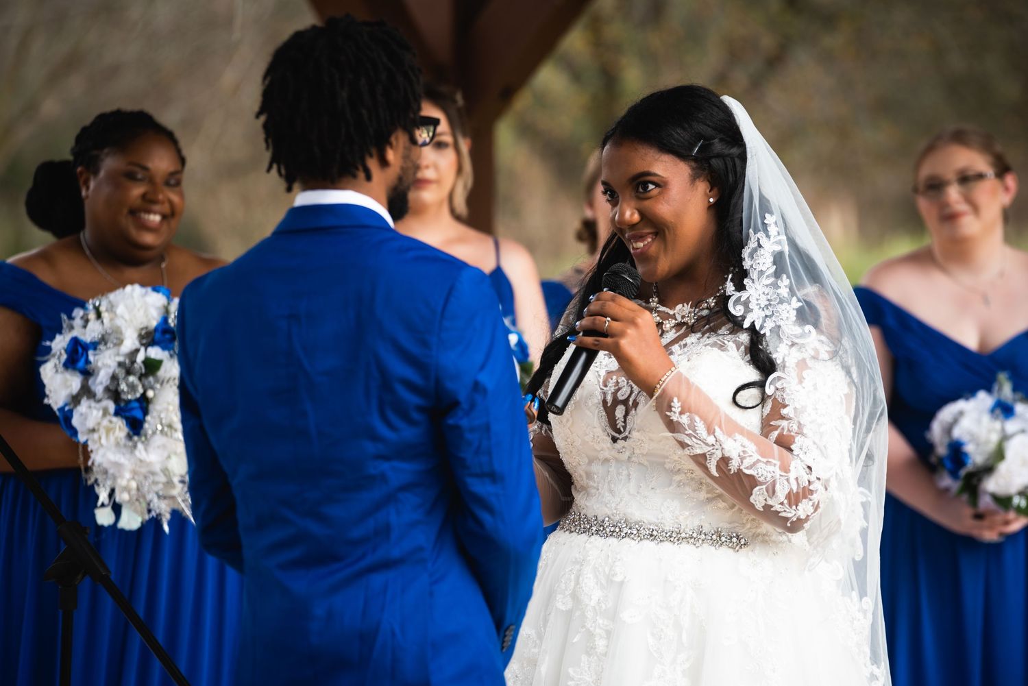 Wedding ceremony with bridesmaids in blue dresses watching couple exchange vows.