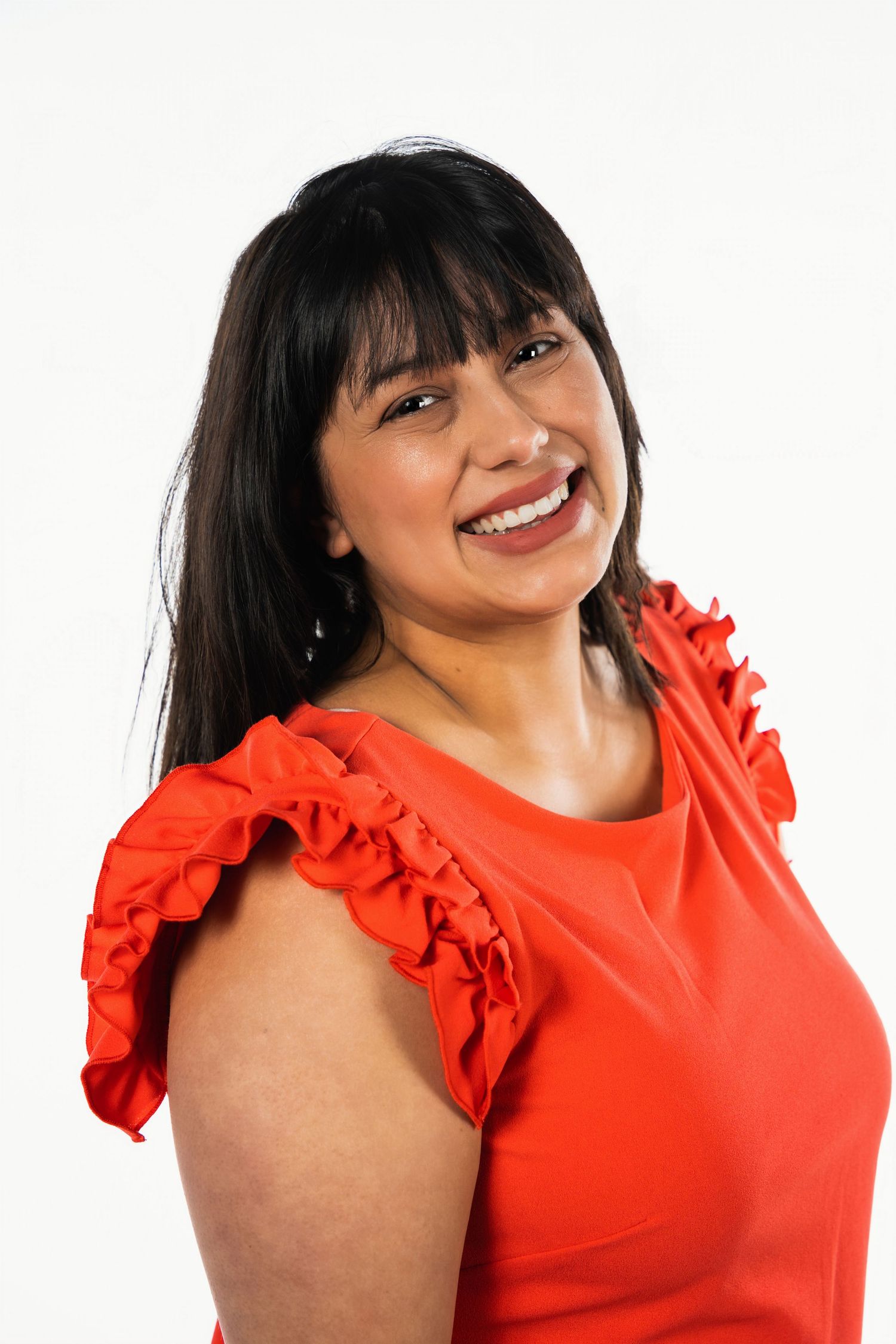 Studio portrait of a woman wearing a bright red ruffled sleeve top against white background.