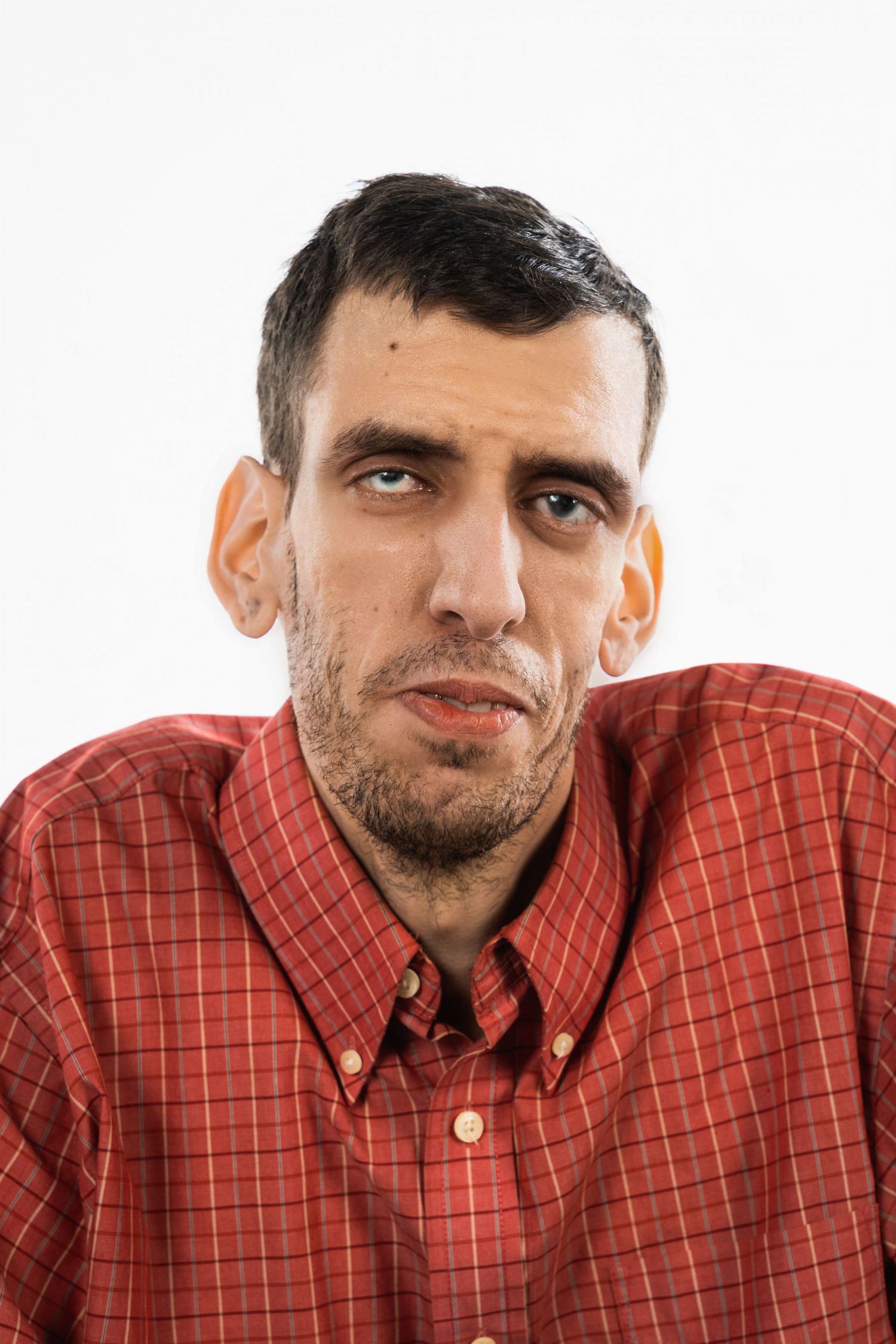 A portrait of a person wearing a red plaid button-down shirt against a white background.