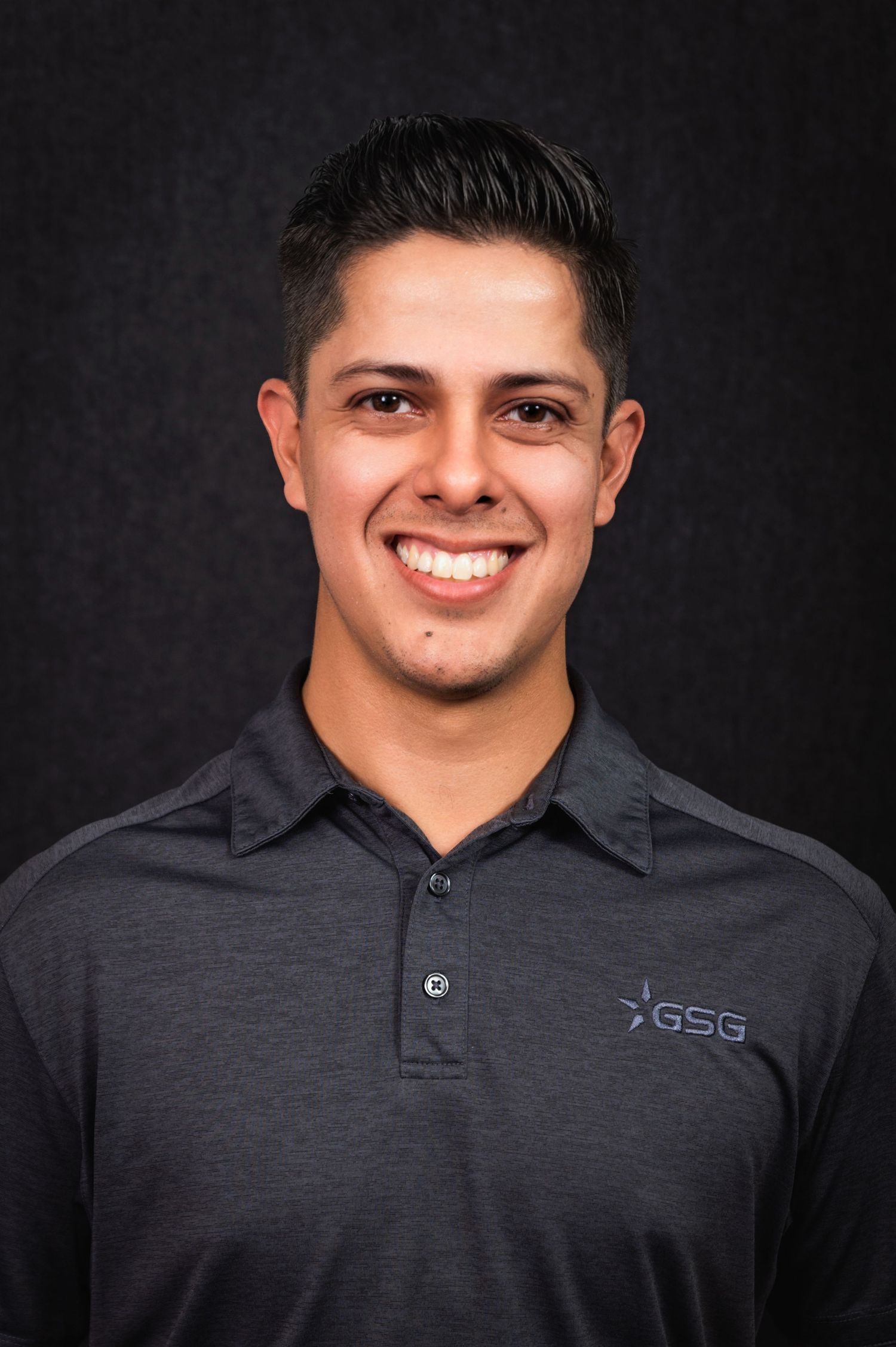 Professional headshot of person wearing dark gray polo shirt with GSG logo against black background.