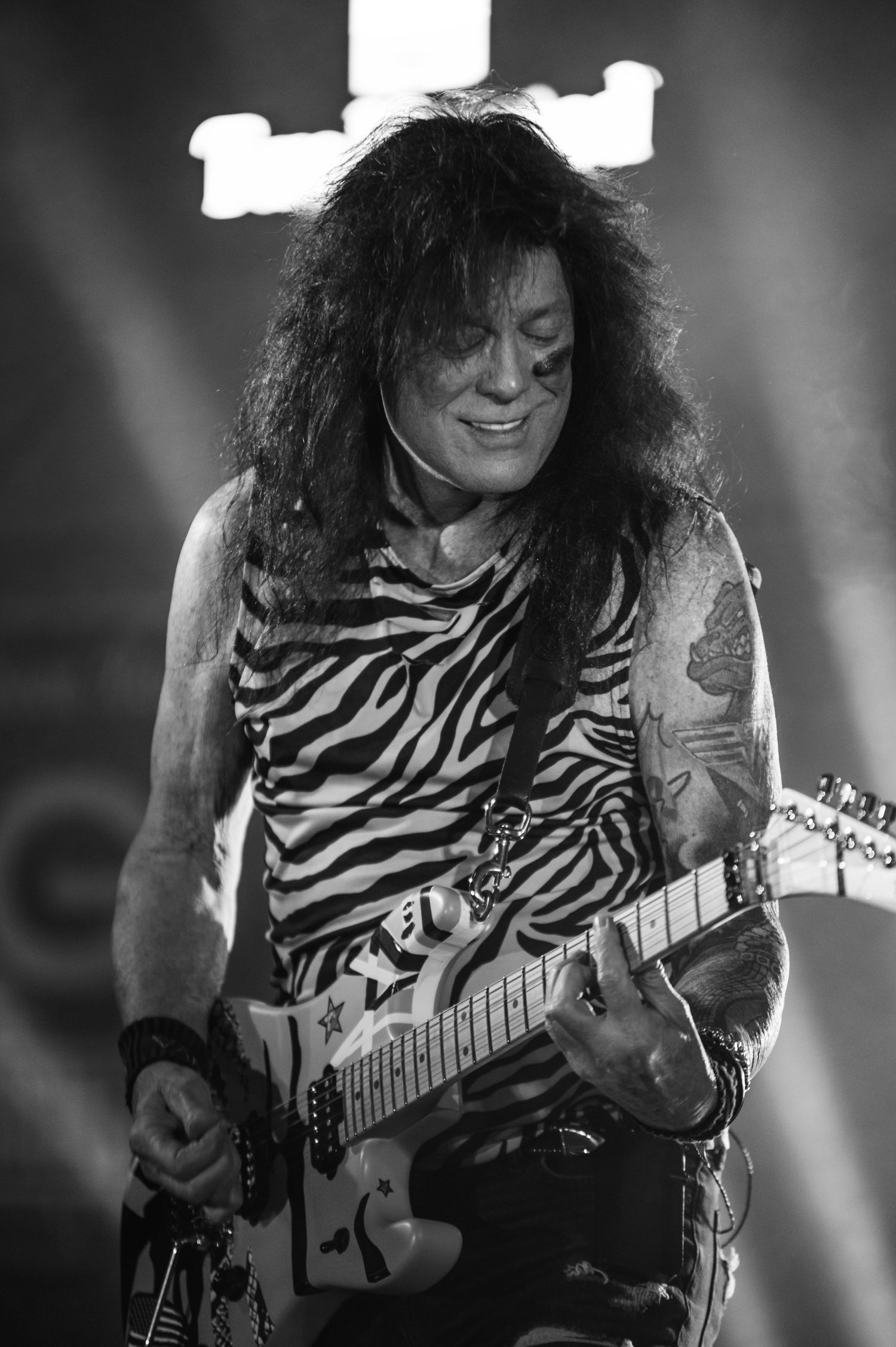 Black and white photo of guitarist playing with dramatic stage lighting.