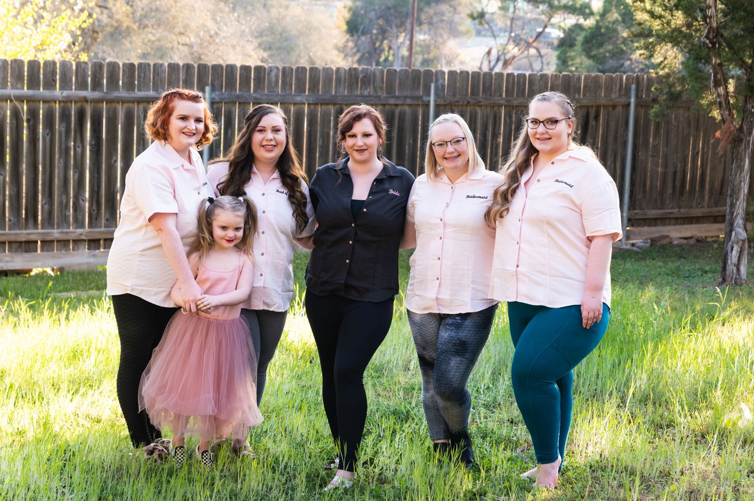 Professional team photo of staff members posing together in a backyard setting.