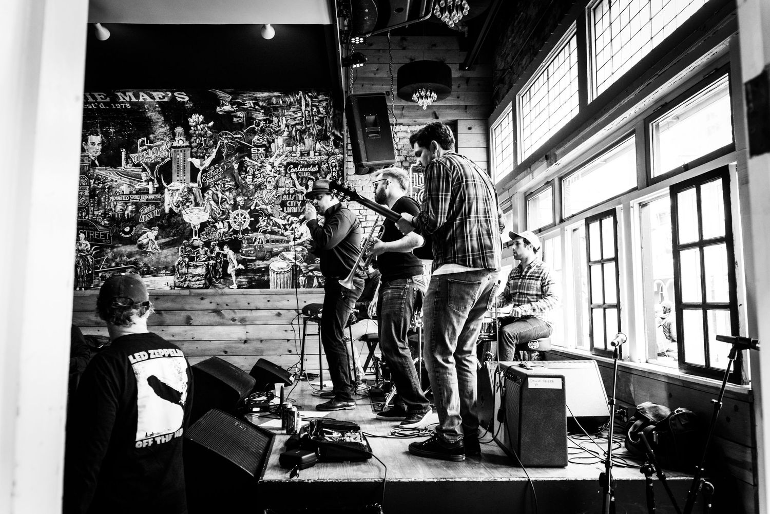 Band members performing energetically on stage in black and white with dramatic lighting effects.