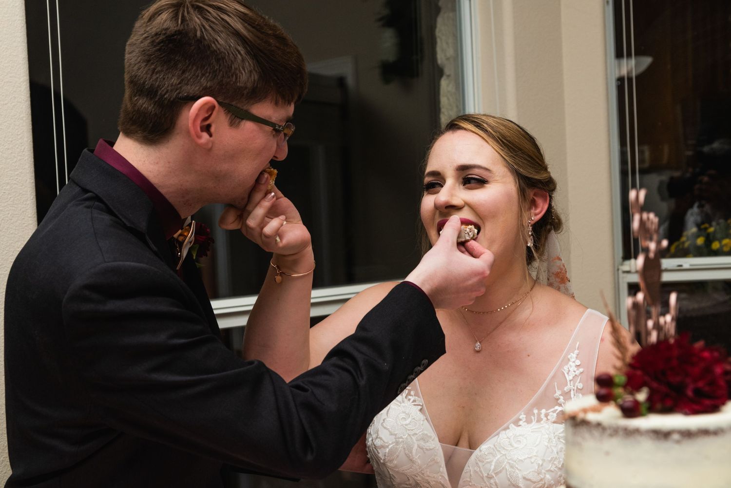 Playful moment of wedding cake feeding between newlyweds at their reception.