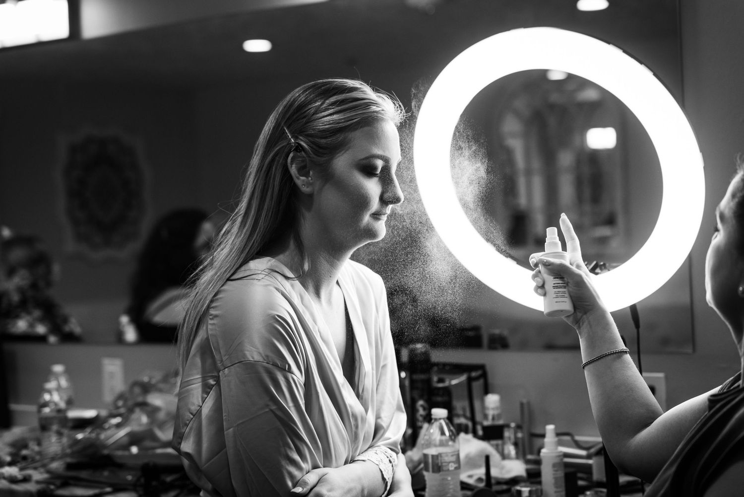 Ring light illuminates makeup session in black and white photography.
