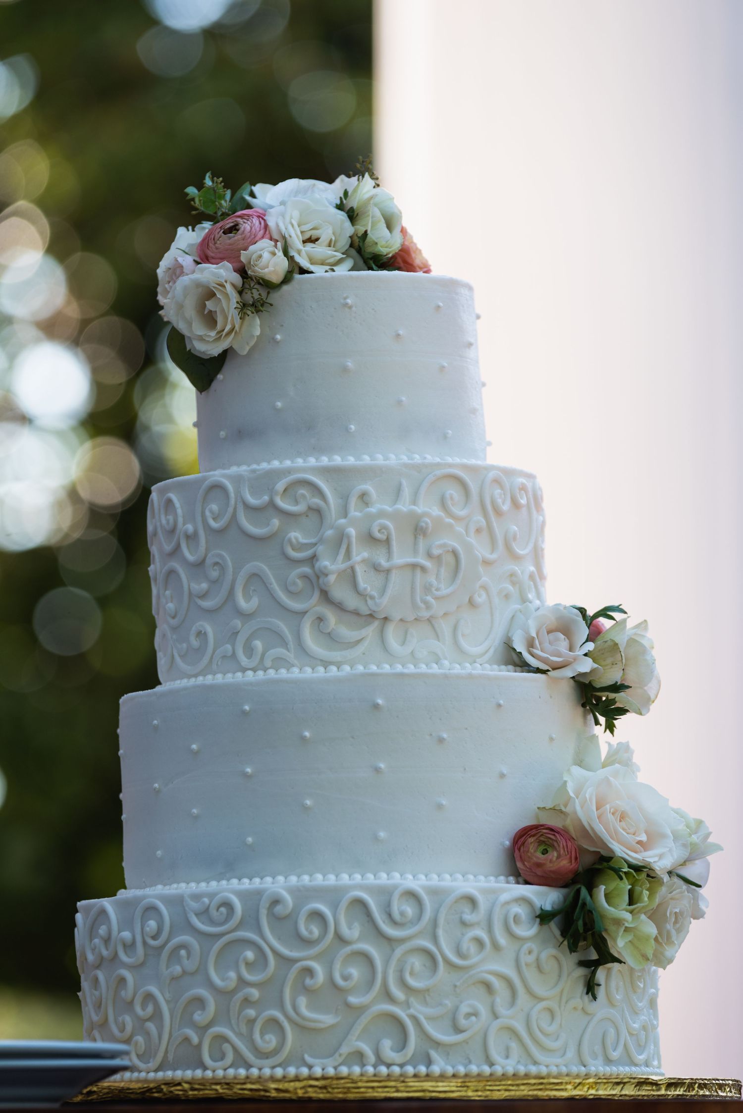 Classic white wedding cake with delicate piping and fresh roses cascading down the tiers.