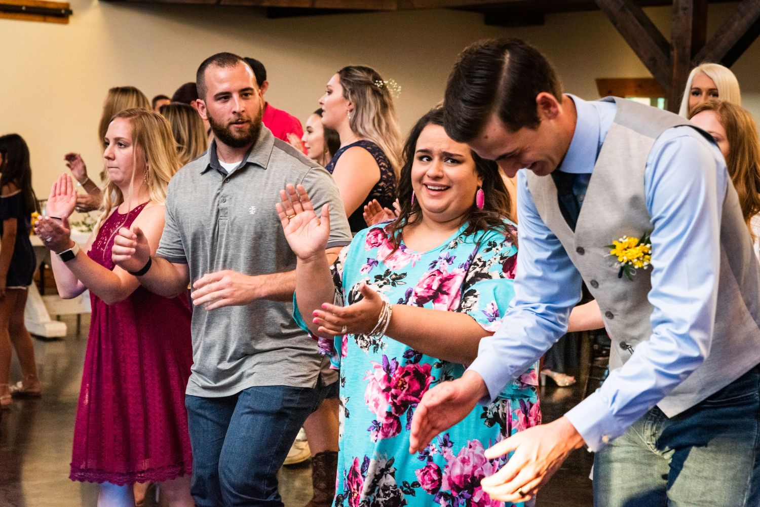 Wedding guests dancing and having fun in a rustic venue with exposed beams.