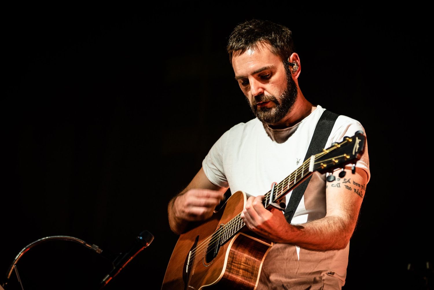 Close-up of guitarist playing acoustic guitar during intimate performance.
