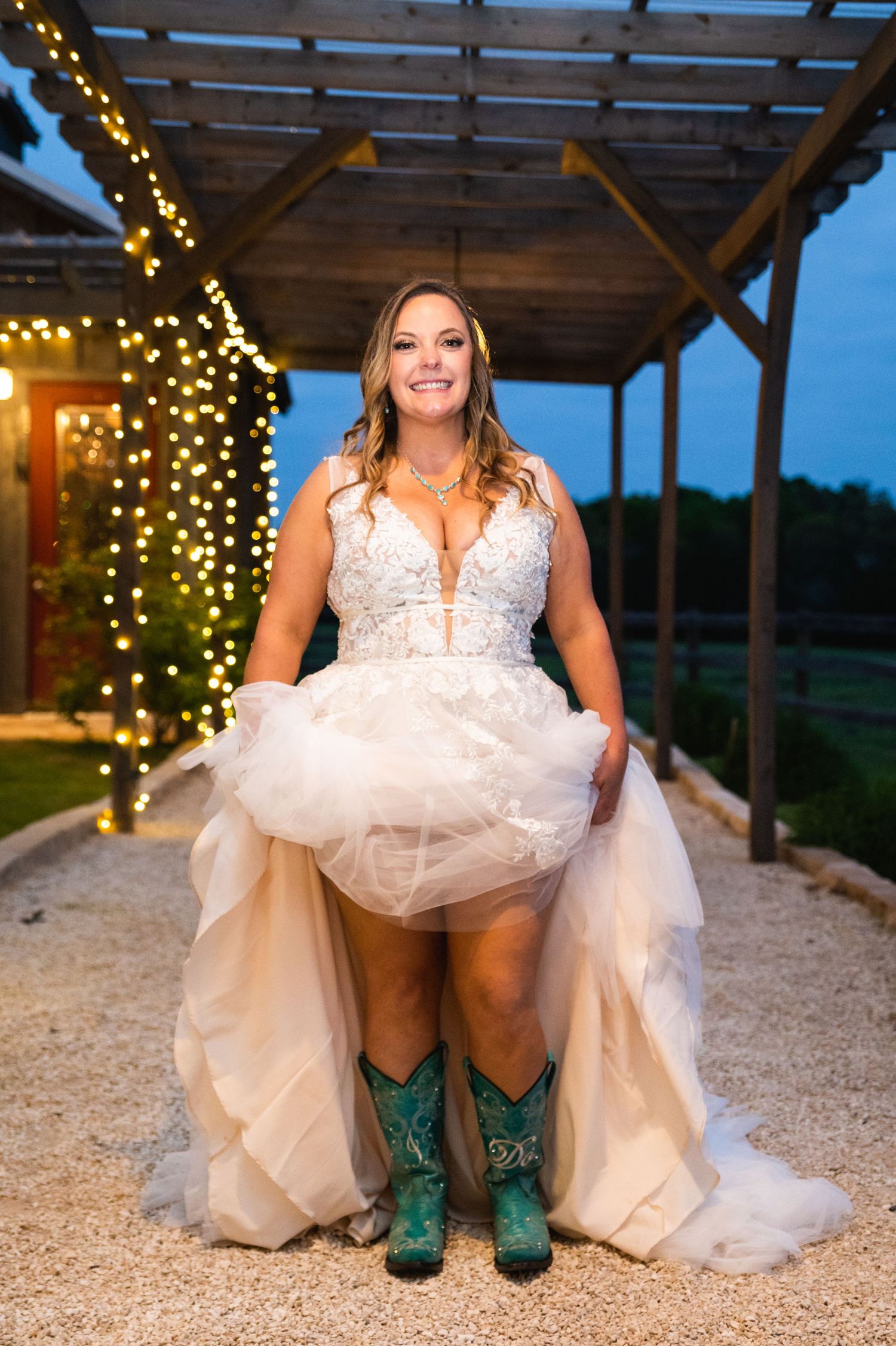 Bride in white dress showing off turquoise cowboy boots under her gown at sunset.