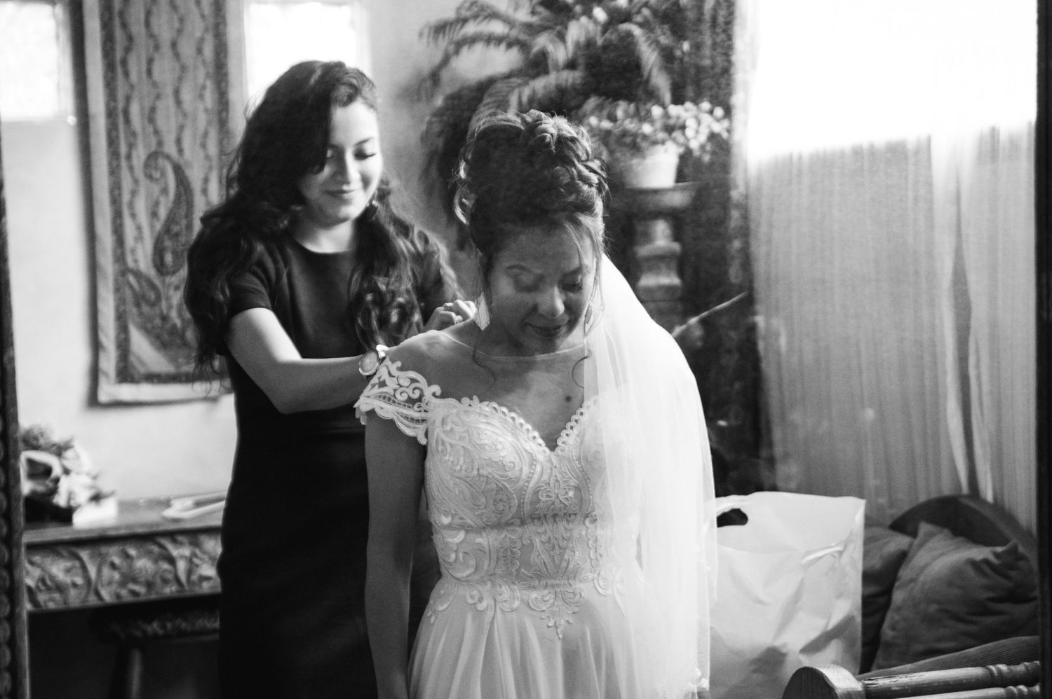 Black and white photo of wedding dress preparation moment.